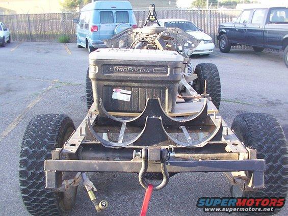 Vehicle frame with ActionPacker box, rear view. Other vehicles and a van are visible