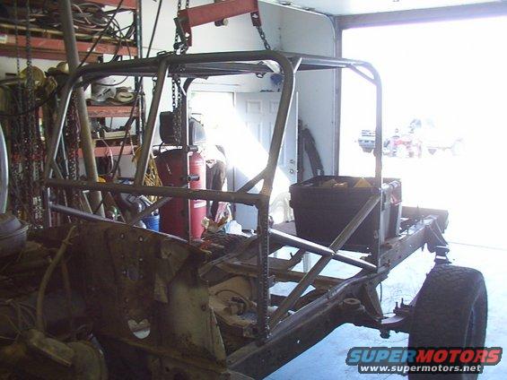Roll cage being welded onto vehicle frame in garage