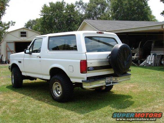 1993 Ford Bronco parked on grass in front of a shed and house, rear view