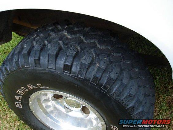 White vehicle's front tire with "RADIAL" text on the sidewall and a chrome rim
