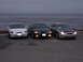 1995 Ford Taurus - Three 1995 Ford Taurus sedans are parked in a line facing the ocean, with their headlights on.