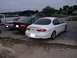1995 Ford Taurus - Several sedans and a pickup truck are parked on a dirt lot near a residential area.