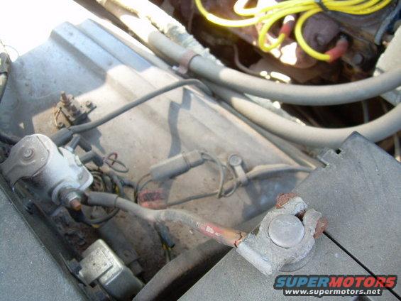 Close-up of corroded battery terminals and yellow spark plug wires in an engine bay