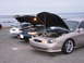 1995 Ford Taurus - Multiple Ford Tauruses with their hoods open are parked in a line near the ocean.