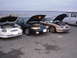 1995 Ford Taurus - Multiple Ford Taurus sedans are lined up with their hoods open, facing the water.