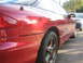 1993 Ford Probe - The rear quarter panel and wheel of a red 1993 Ford Probe are visible, with another car parked behind it.