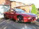 1993 Ford Probe - A red 1993 Ford Probe coupe is parked in front of a brick house and garage.