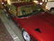 1995 Ford Taurus - A red coupe with a tan interior is parked on a street next to other vehicles.
