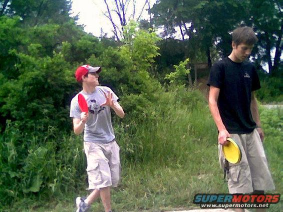 guy in red hat throwing a red disc, another guy holding a yellow disc