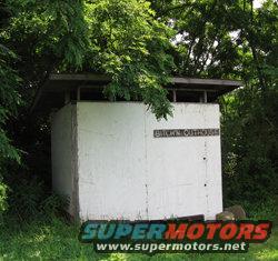 Outhouse with "BROWN'S OUTHOUSE" sign. Supermotors.net logo at bottom