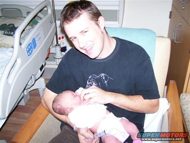 Man holding newborn baby in hospital room