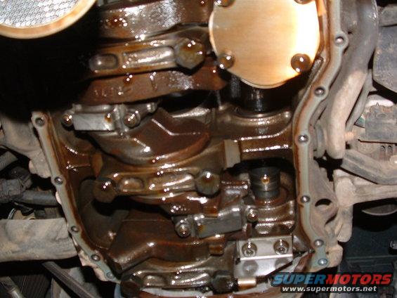 Engine crankshaft and connecting rods with oil. Watermark reads SUPERMOTORS.NET