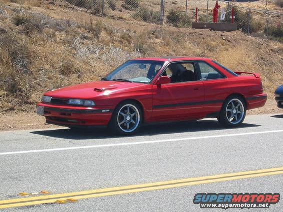 Red 1989 Mazda MX-6 coupe parked on roadside, seen from the front-left