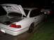 1992 Ford Crown Victoria - A white sedan is parked at night with its trunk open, and another car is visible behind it.