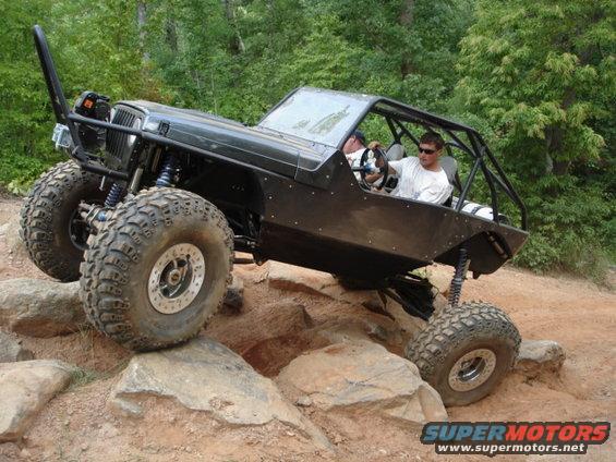 Modified Jeep Wrangler climbing over rocks on a trail