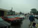 1978 Ford Mustang II - Several Ford Mustangs are parked on a wet street during an outdoor car show.