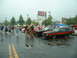 1978 Ford Mustang II - A group of cars and people are gathered in a wet parking lot, with several classic Mustangs on display.