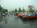 1978 Ford Mustang II - Several classic cars, including a black and orange Cobra, are parked in a lot on a rainy day.