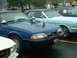 1978 Ford Mustang II - A blue police car, likely a 1987 Ford Mustang GT, is parked next to other vehicles at an outdoor event.