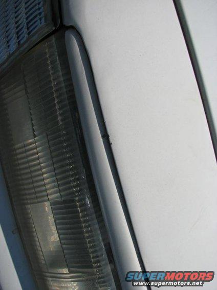 Close-up of a white vehicle's headlight and fender area