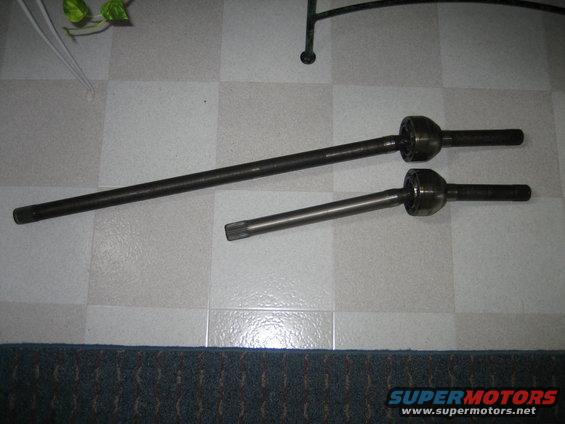 Two dark metal drive shafts with spherical joints on a checkered floor
