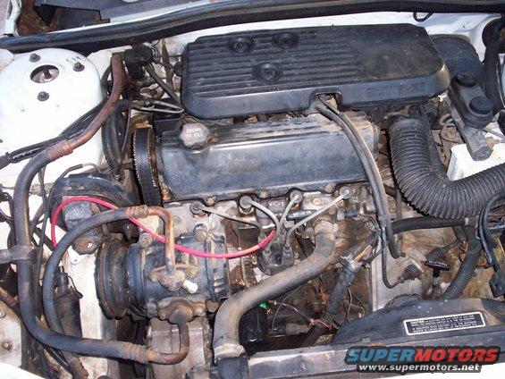 Engine bay with visible engine components, hoses, and wiring. Watermark reads SUPERMOTORS