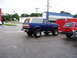 1989 Ford Bronco - Lifted 1989 Ford Bronco in blue with a tan top is parked on a wet street.