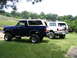 1989 Ford Bronco - Two lifted Ford Bronco SUVs are parked side-by-side on a grassy lawn.
