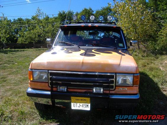 1991 Ford Bronco front view with orange paint and black flame decals, bull bar, and roof lights
