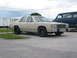 1985 Ford Crown Victoria LTD - A tan sedan with a blue hood accent sits parked on asphalt next to a dark blue van.