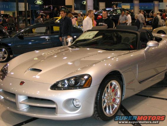 Silver convertible Dodge Viper SRT-10 with red brake calipers. Other cars and people in background