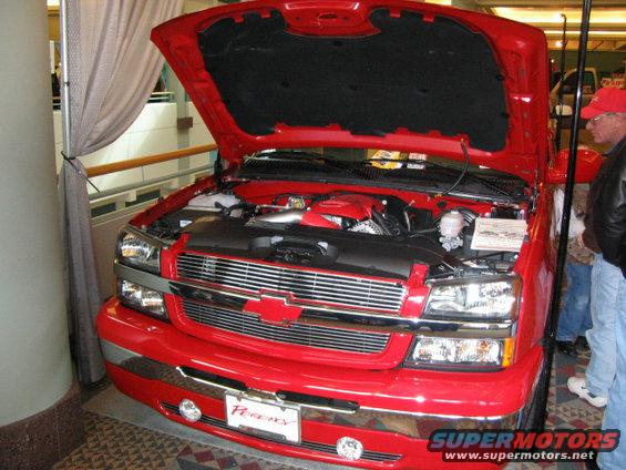 Red pickup truck front view, hood open, showing engine. "Performance" plate visible