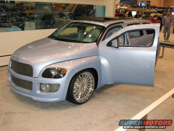 Light blue custom van with open driver's door, aftermarket grille, and large chrome wheels