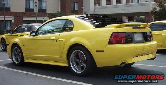 Yellow Mustang GT parked next to another yellow car. Rear view shows louvers on the back window and a spoiler