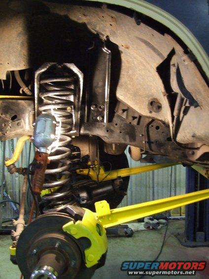 Close-up of yellow-painted brake caliper and suspension components on a vehicle