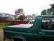 1996 Ford Bronco - A green 1996 Ford Bronco is seen from the side, partially obscured by another vehicle.