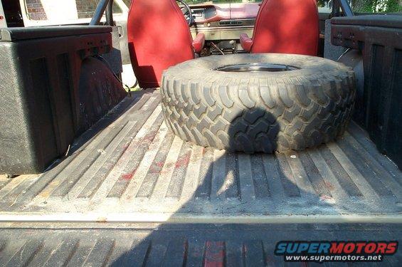 Spare tire in pickup truck bed, red seats visible
