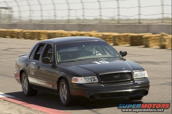 Black 1999 Ford Crown Victoria with racing numbers on track