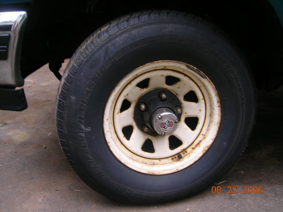 Close-up of a white-painted steel wheel with a black hubcap and a Cooper Discoverer Radial tire. Date stamp 08.25.2006 visible