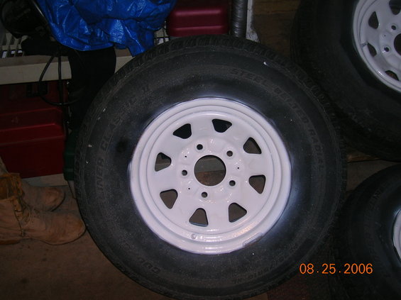 White painted rim with black tire, showing "STEEL BELTED RADIAL" text and date stamp