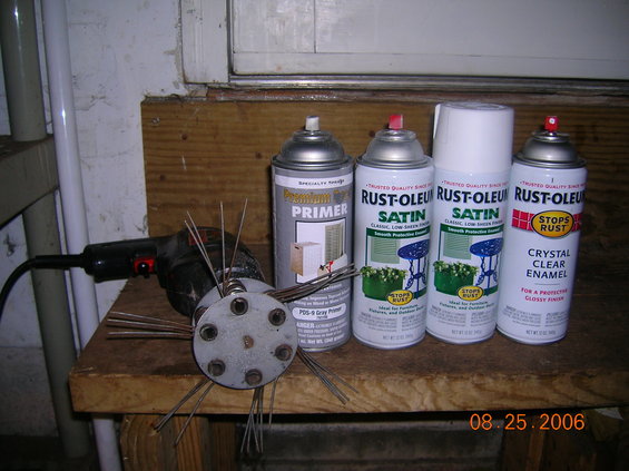 Wire wheel brush attachment and spray paint cans on a wooden surface