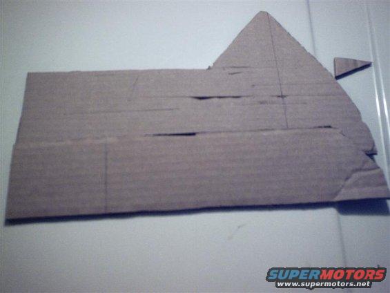 Again, I only have the 2 hands, so use your imagination.

What we have to do to correct the gap is this: using some method of your choosing (I used masking tape and one hand), hold the original cardboard template flush with the bottom of the base. Then take another piece of cardboard which is the right length and angle it so that it is flush with the floor.

Mark the line where the two pieces meet.