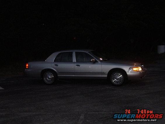 Silver sedan parked at night, side view. The car has a chrome grille and alloy wheels