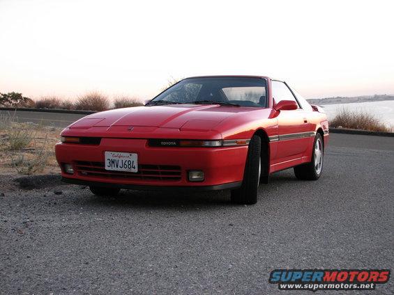 Red Toyota Supra with pop-up headlights and California plates