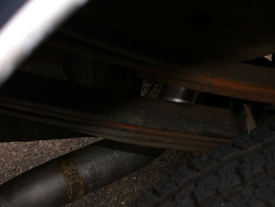 Close-up of a vehicle's exhaust pipe and leaf springs