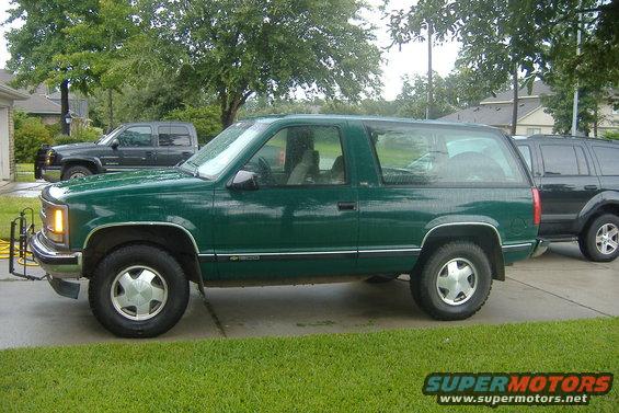 Green two-door SUV parked next to a black SUV. It has a chrome trim line along the side