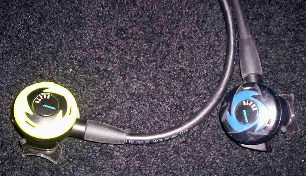 Yellow and blue scuba regulators with hoses on dark carpet