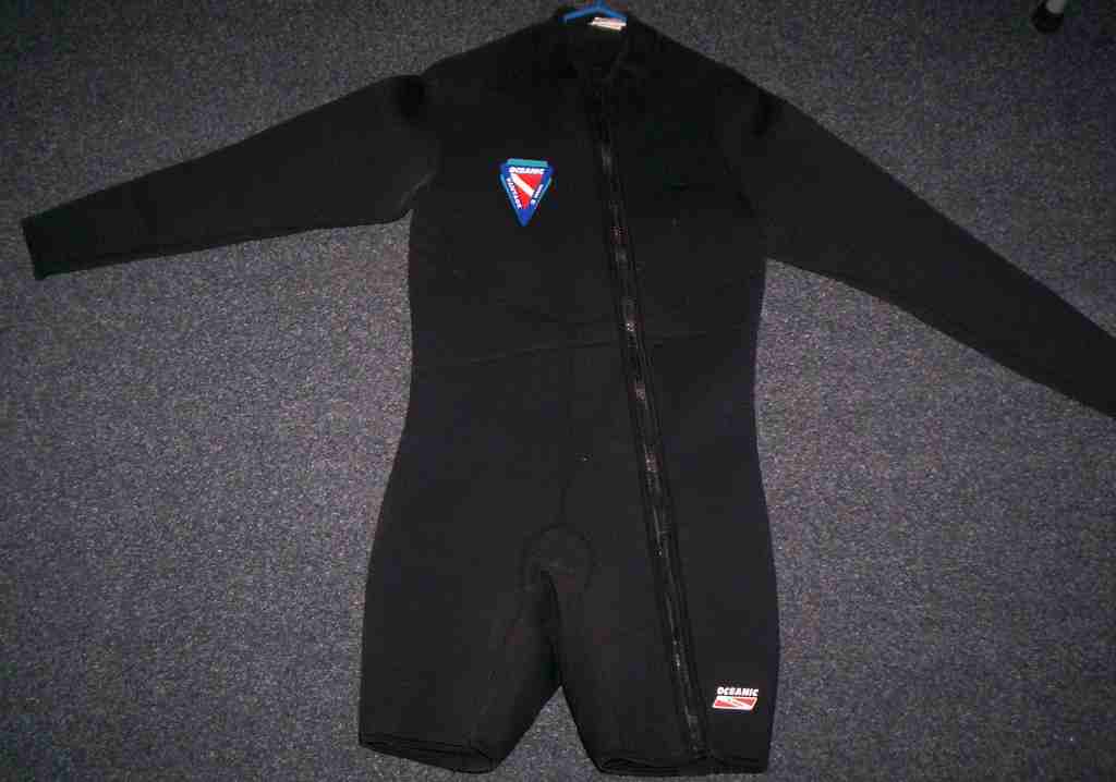 black wetsuit with blue and red dive flag logo on chest, zipper down front, and oceanic logo on leg