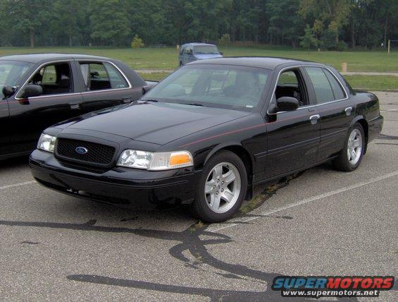 Black Ford Crown Victoria parked next to another black Crown Victoria