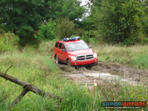 Red Dodge Durango with light bar stuck in mud off-road